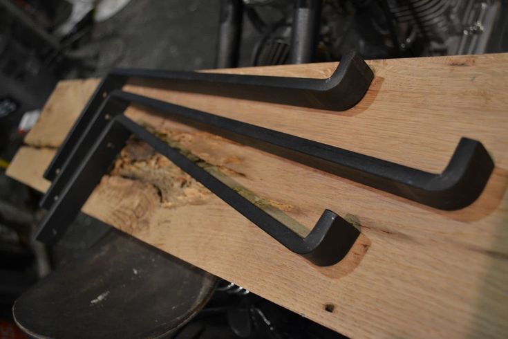 three black metal handles on a wooden board