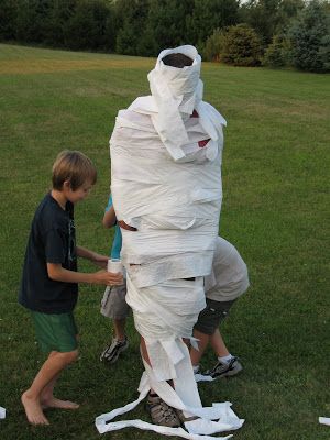 two boys are playing with a giant paper mache in the grass while another boy looks on