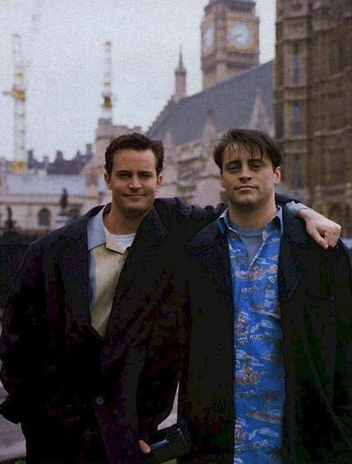 two men standing next to each other in front of a clock tower