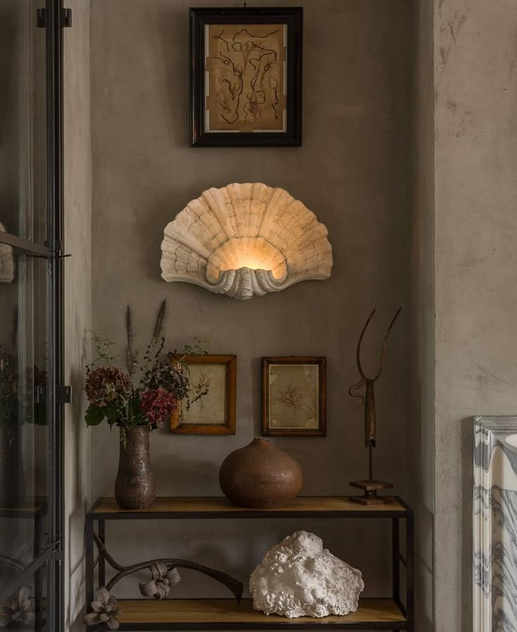 a shelf with vases and pictures on it in front of a wall mounted fan