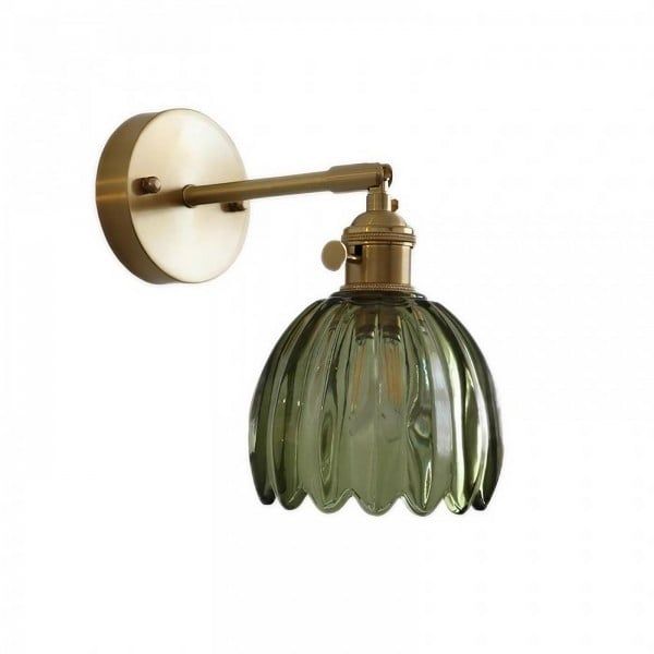 an old fashioned wall light with a green glass shade on it's head and arm