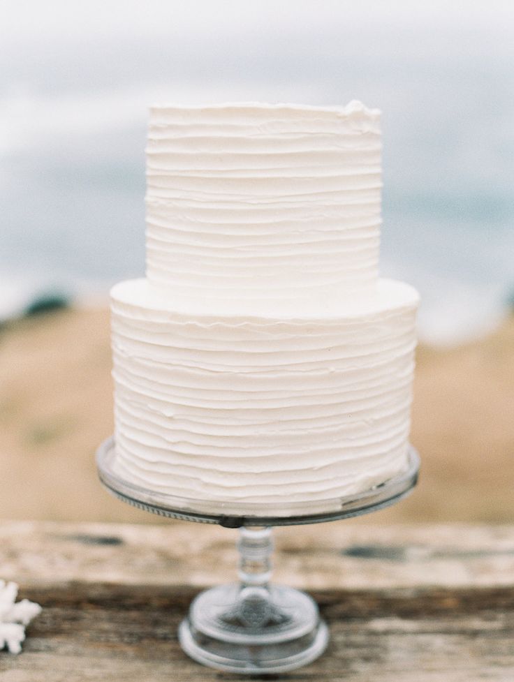 a white frosted cake sitting on top of a wooden table