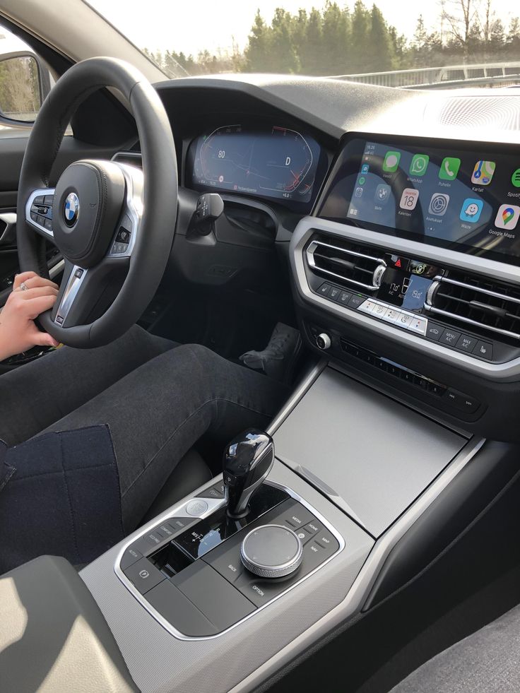 a woman is sitting in the driver's seat of a car with her hands on the steering wheel