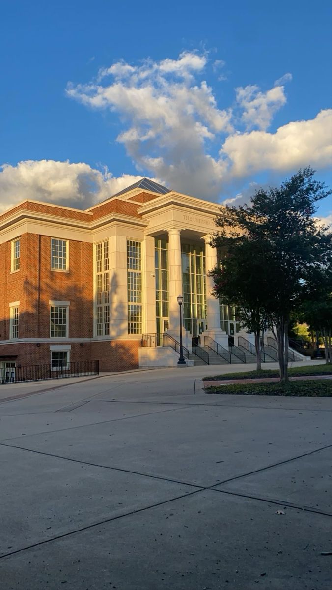 a large building with many windows and trees in front of it on a sunny day