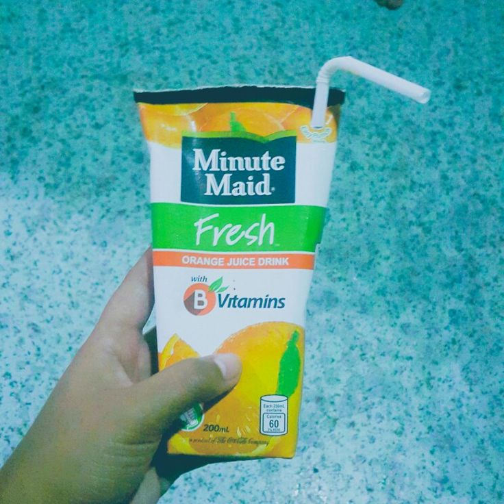 a hand holding a carton of orange juice with a straw sticking out of it