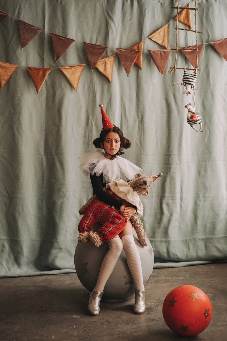 a woman in a costume sitting on top of a ball