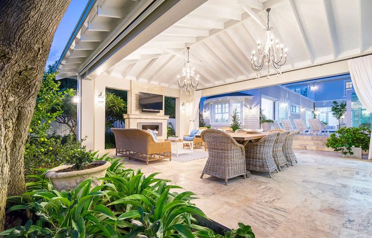 an outdoor dining area with chairs and tables under a white roof over looking the ocean