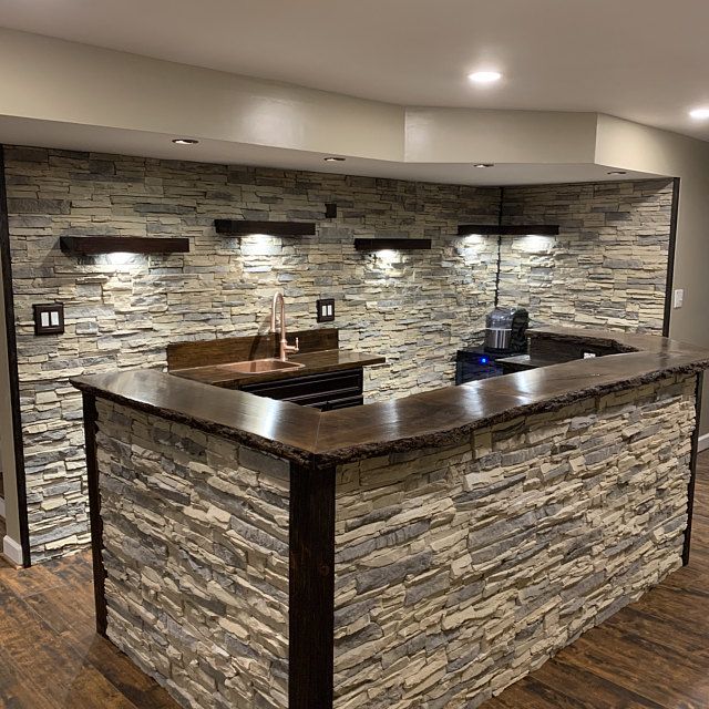 a kitchen with an island made out of stone and lights on the wall above it