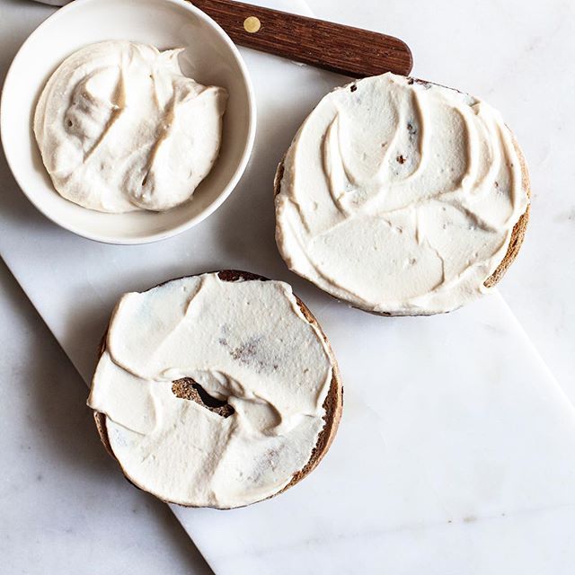 three white frosted desserts sitting on top of a counter next to a wooden spoon