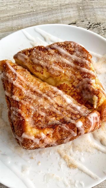 two pieces of french toast sitting on top of a white plate covered in icing