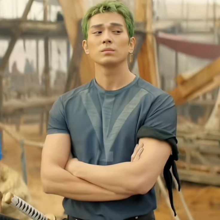 a young man with green hair is standing in front of construction equipment and looking at the camera