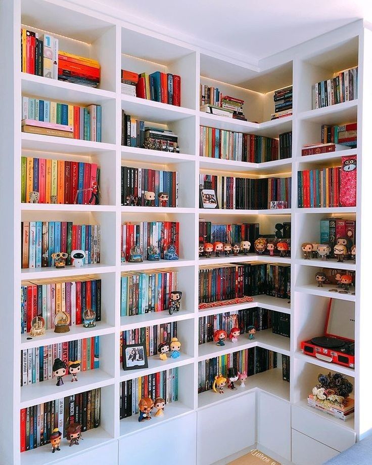 a book shelf filled with lots of books on top of white shelving unit units