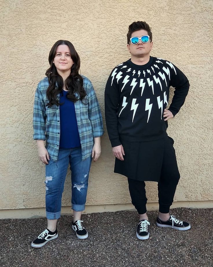 two people standing next to each other in front of a wall with lightning sweaters on