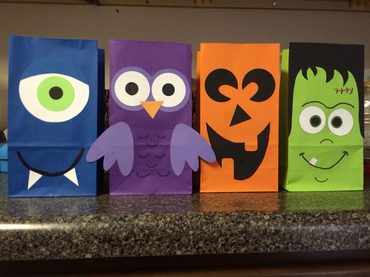 four bags decorated to look like halloween characters on a kitchen counter with eyes, nose and mouth