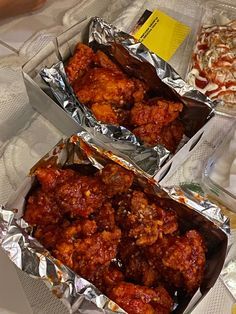 two tin foil trays filled with food on top of a white tablecloth covered table