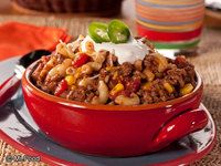 chili macaroni and cheese in a red bowl with a spoon on the side