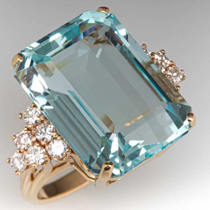 This fabulous ring is centered with an emerald cut aquamarine, weighing 23.83 carats, in a four-prong setting. The shoulders are each prong set with six (6) round brilliant cut diamonds. The ring measures 20.2mm at the top, rises 11.5mm above the finger, tapering to 2.7mm wide and 1.6mm thick at the base of the shank. It is current a size 6.25. The ring is slightly oval due to previous sizing. The aquamarine has some very light wear that is not visible to the unaided eyes. Luxury Unique Aquamarine Ring, Luxury Green Aquamarine Ring, Luxury Aquamarine Round Cut Rings, Blue Aquamarine Emerald-cut Diamond Ring, Aquamarine Stone Ring, Luxury Aquamarine Emerald-cut Rings, Aquamarine Cocktail Ring, Aquamarine Ring Vintage, Glam Jewelry