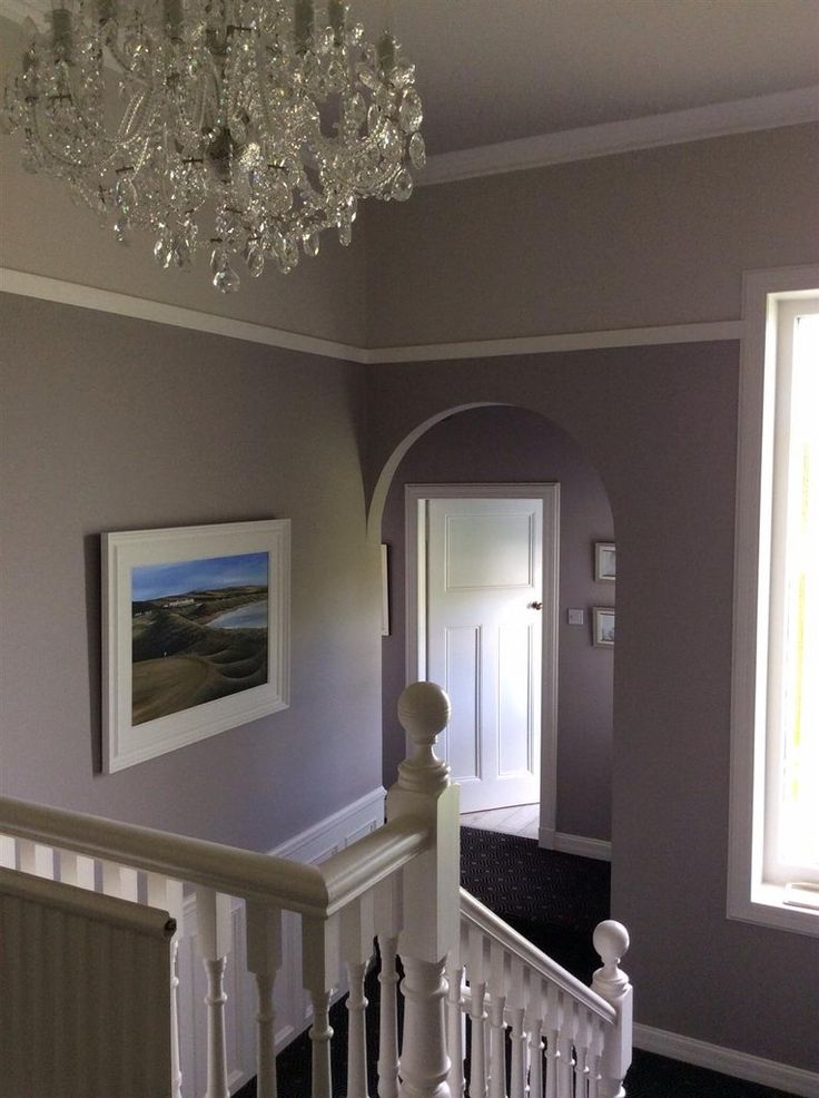 a white staircase with chandelier and pictures on the wall in front of it