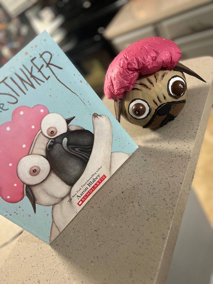 a book with an image of a pug wearing a pink hat next to it