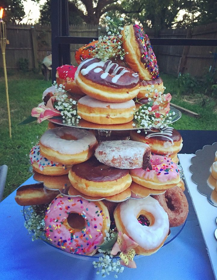 a tower of doughnuts on top of a blue table cloth in the back yard