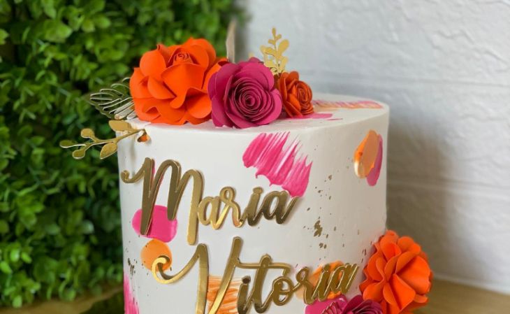 a white cake with orange and pink flowers on it's side that says marra mitton