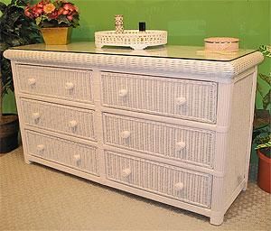 a white wicker dresser sitting in front of a green wall