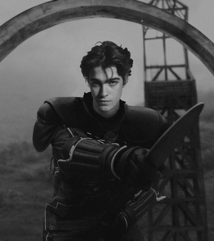 black and white photograph of a man holding a large knife in front of an arch