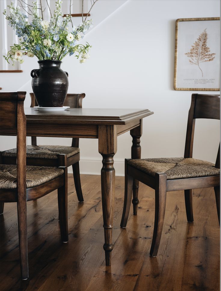 a wooden table with two chairs and a vase on it