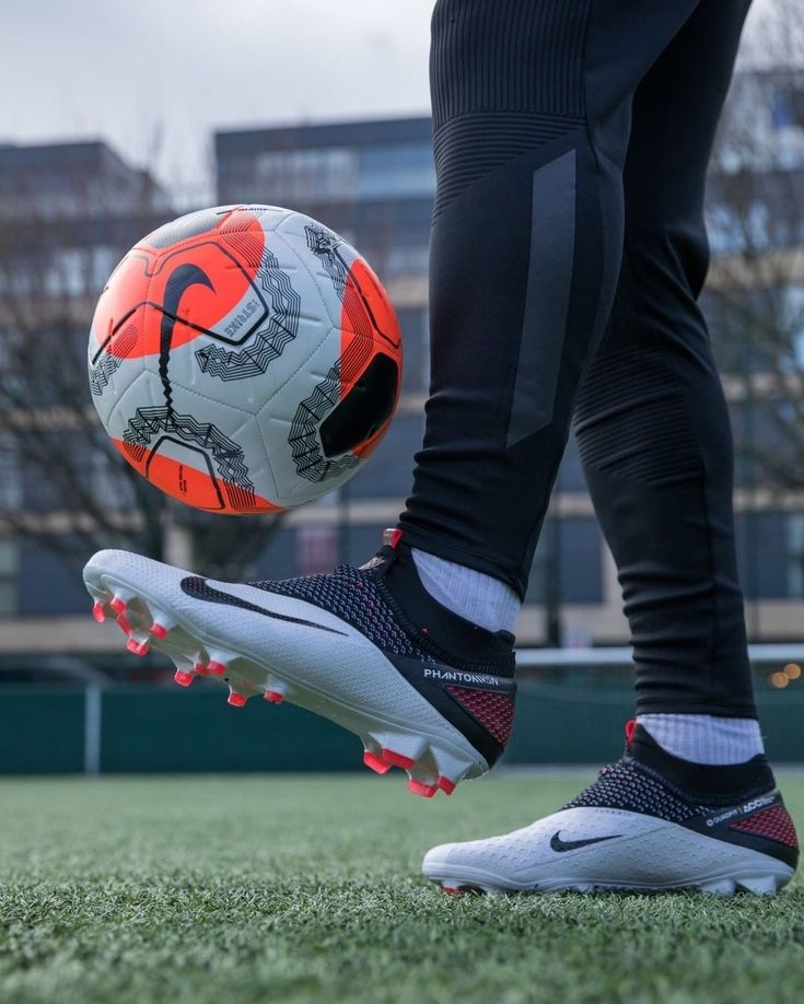 a person standing on top of a field with a soccer ball in their hand and shoes