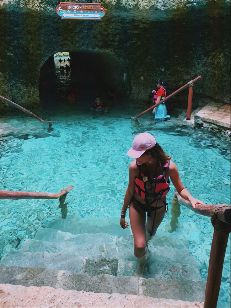 a woman in a pink hat is walking up some stairs into a blue swimming pool