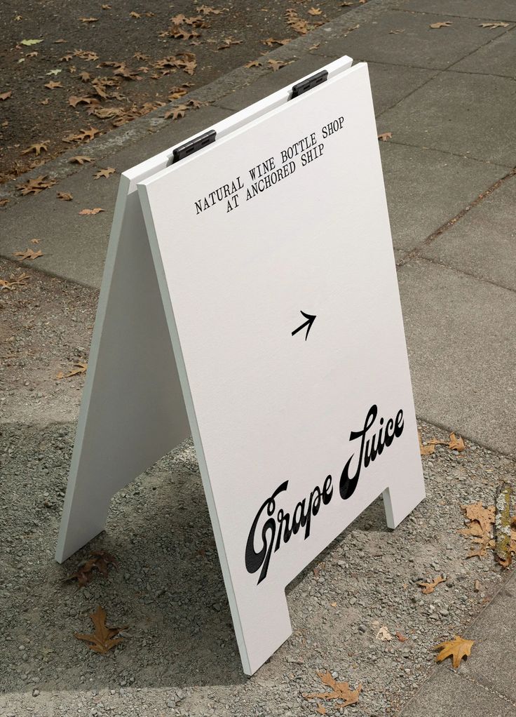 a white sign sitting on the side of a road with an arrow pointing to it