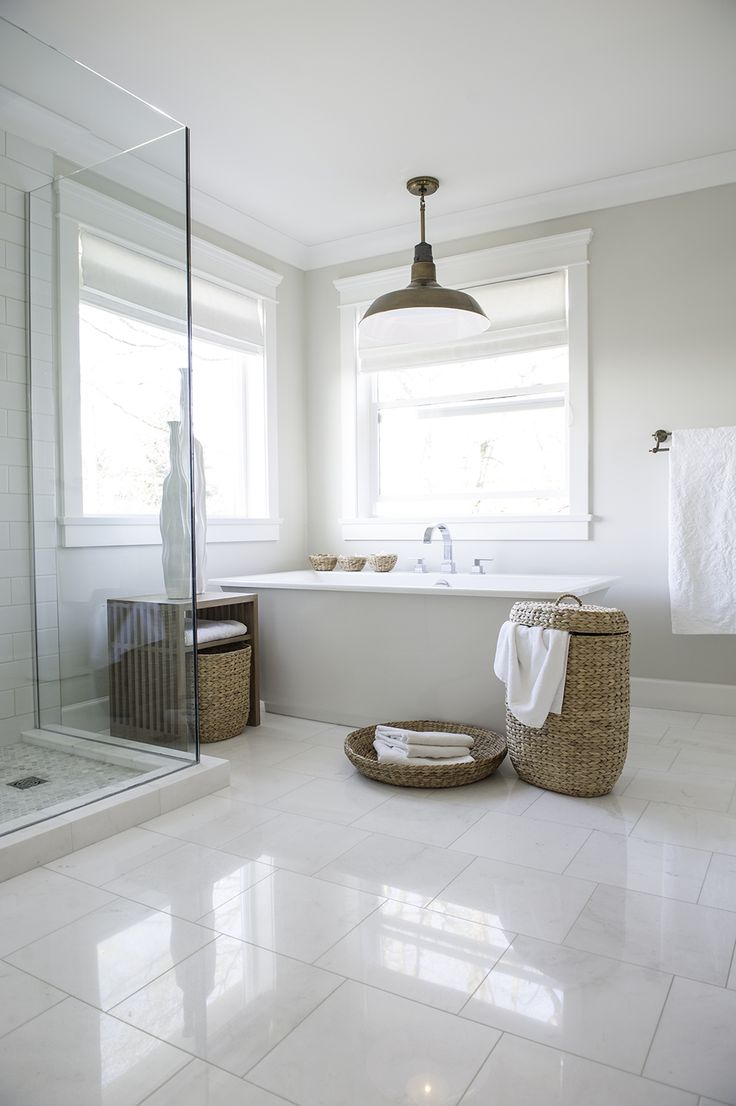 a bathroom with white tile floors and large windows