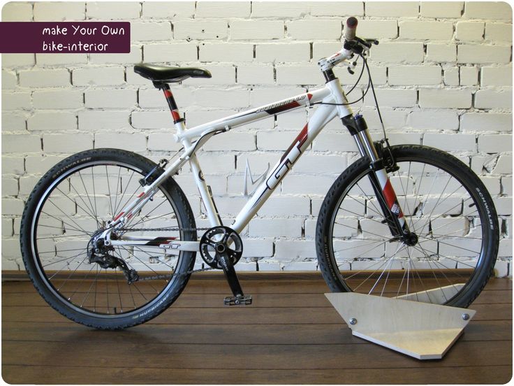 a white bike with red and black accents on it's front wheel is standing in front of a brick wall