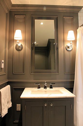 a white sink sitting under a bathroom mirror next to a shower curtain and two lights