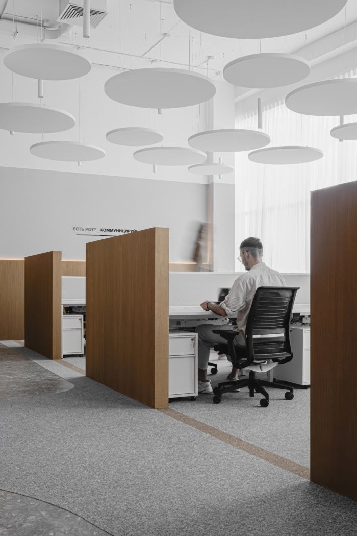 a man sitting at a desk in an office with lots of lights hanging from the ceiling