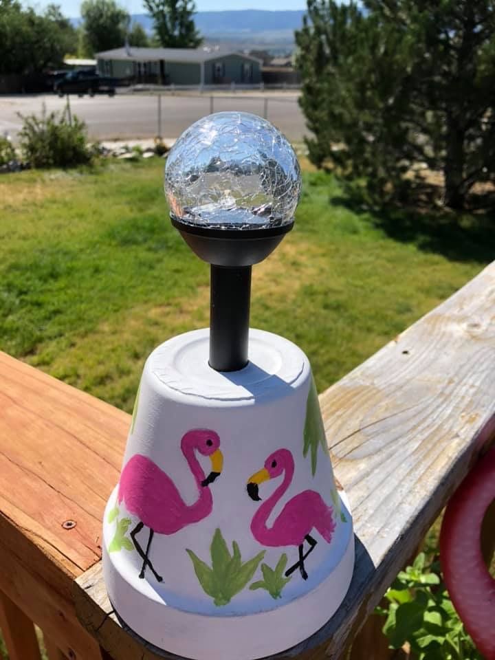 a pink flamingo lamp sitting on top of a wooden fence