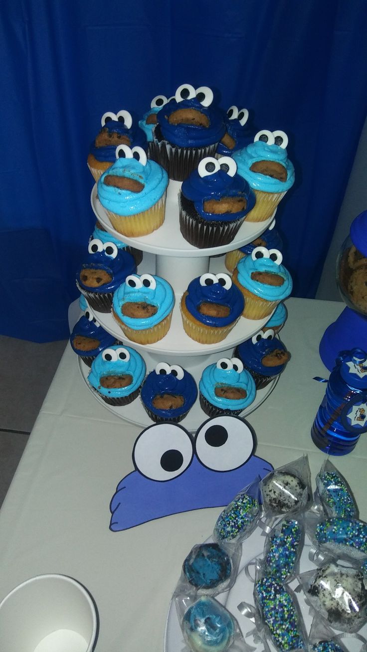 a table topped with cupcakes covered in blue frosting and cookie monster decorations