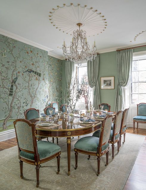 a dining room table with blue chairs and a chandelier hanging from the ceiling