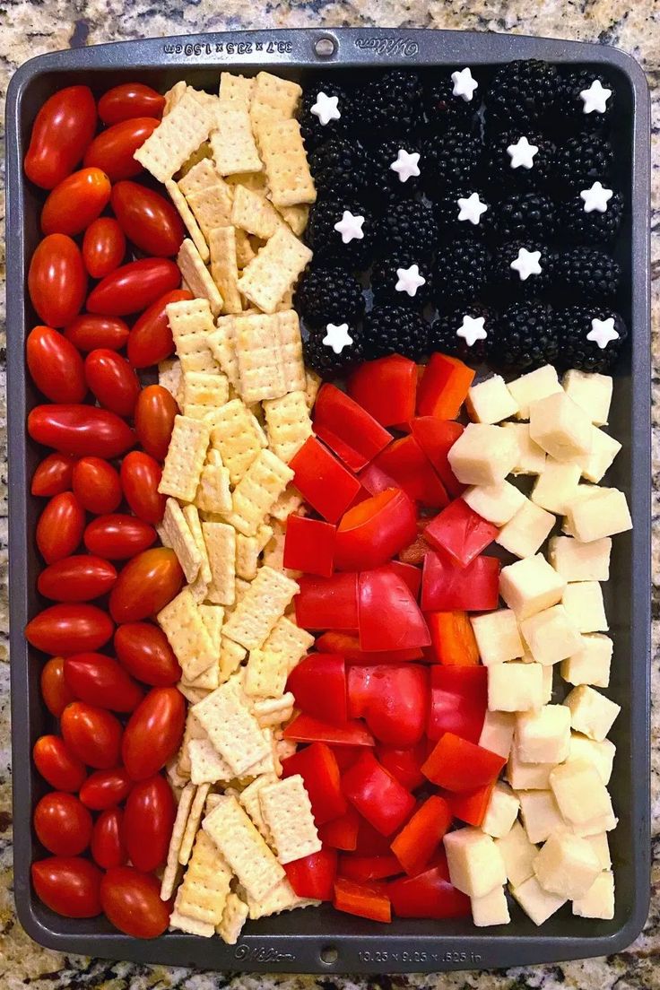 an american flag made out of crackers, tomatoes and blackberries in a container