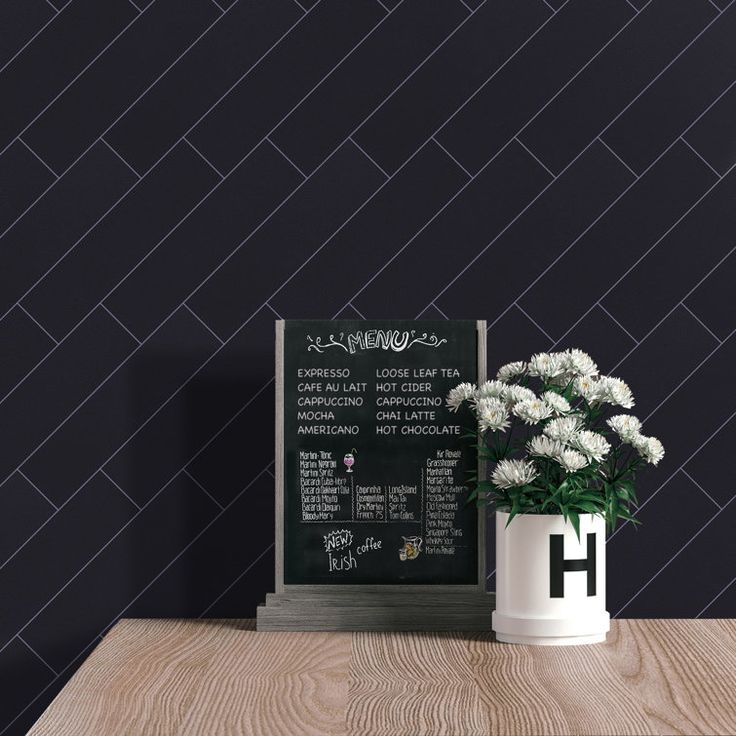 a vase with flowers on a table next to a chalkboard sign and black chevron wallpaper