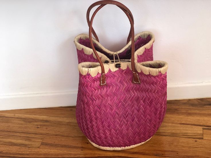 These beautiful pieces are designed in South Africa. Handmade with raffia and featuring leather handles, these bags bring the perfect mix of bohemian chic to everyday wear! Capable of being used as a handbag, basket or storage-this multi-purpose piece is a cannot miss! The double closure top provides a multi-style capability as well! Sizing: 16 inches wide x 12 inches deep x 13 inches high Pink Bucket Bag With Braided Handles And Top Handle, Bohemian Straw Bag With Bamboo Handle For Shopping, Bohemian Bucket Bag With Braided Top Handle, Shopping Basket Shoulder Bag With Leather Handles, Bohemian Bag With Braided Handles For Shopping, Bohemian Bags With Braided Handles For Shopping, Chic Bags With Bamboo Handle For Market, Chic Bamboo Handle Bag For Market, Chic Market Bags With Bamboo Handle