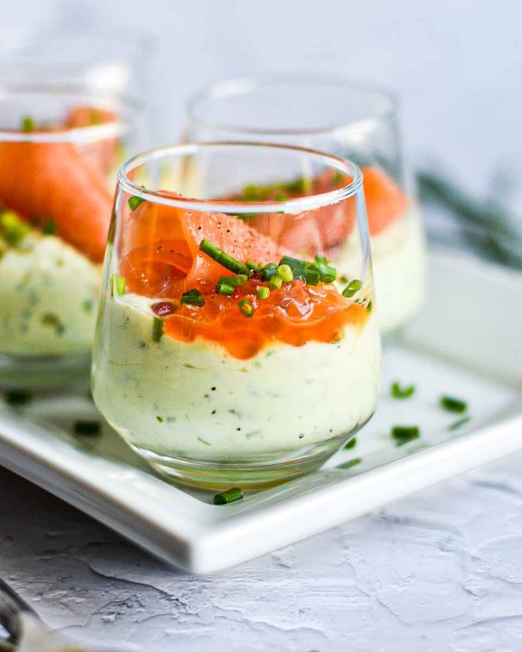 two glasses filled with food on top of a white plate