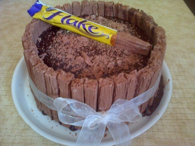 a chocolate cake on a plate with a candy bar in the middle and a bow around it