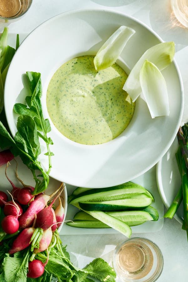 a white plate topped with lots of veggies next to a bowl of dip