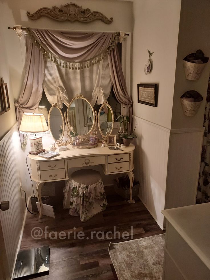 a dressing table and mirror in a room with wood flooring, white walls and curtains