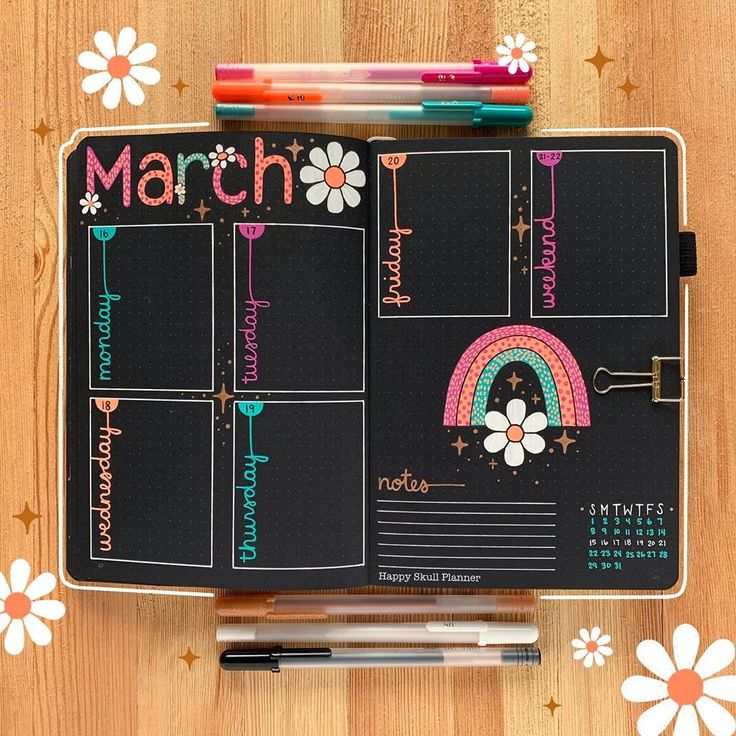 a planner with markers and pencils on top of it, next to some flowers