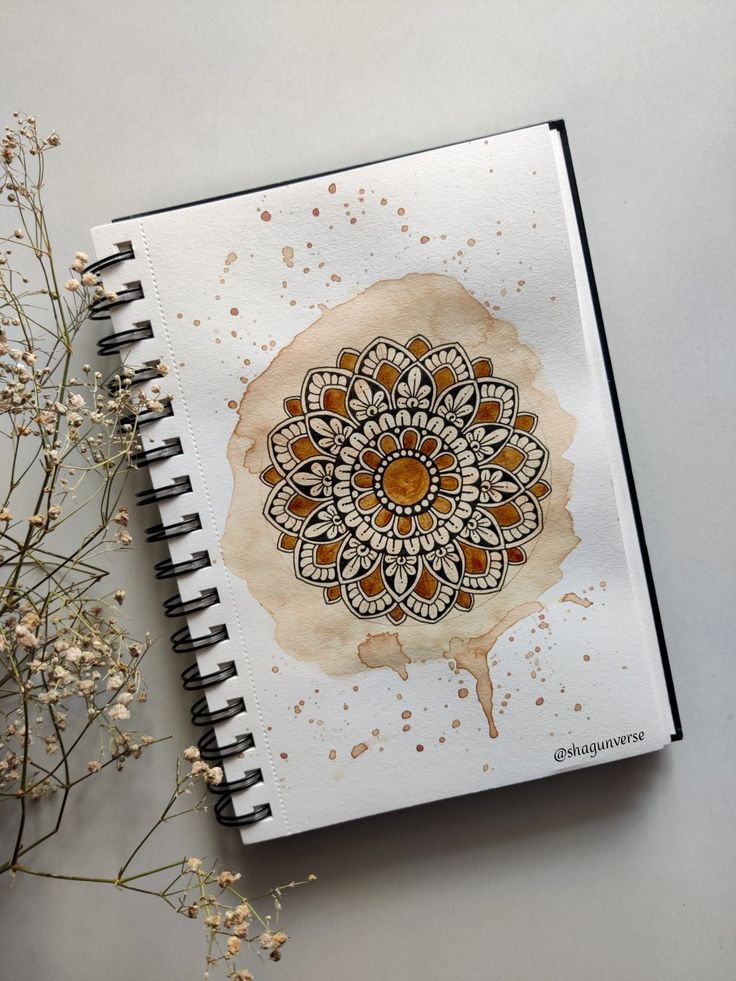 an open notebook with a drawing on it next to some dried flowers and branches in the background