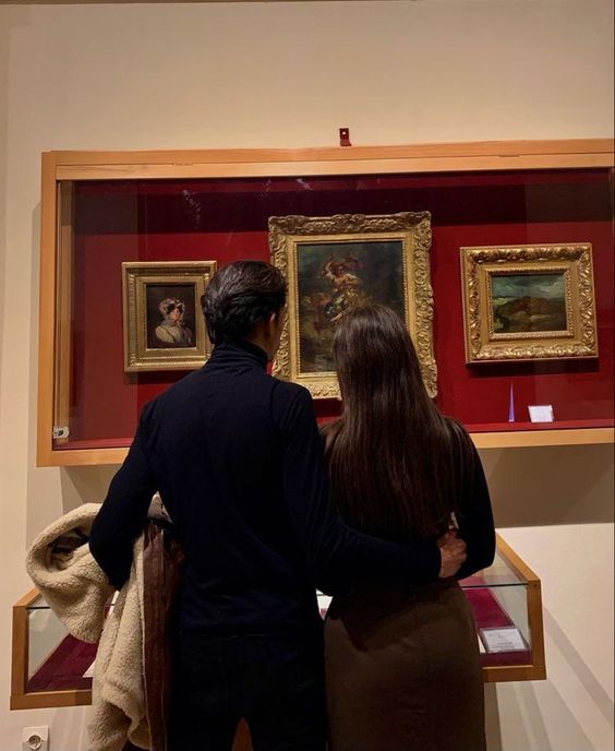 two people looking at paintings on display in a museum