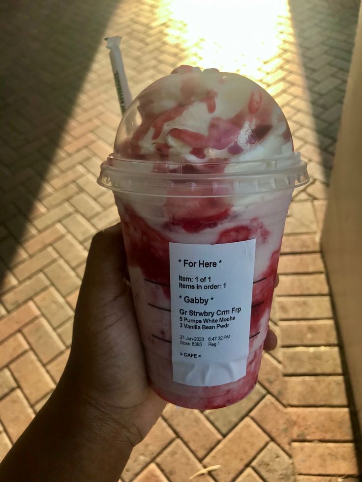 a person holding up a cup of ice cream