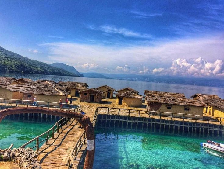 there are many huts on the pier by the water